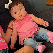 Ariah joined the competition — help win amazing prizes! baby, child, girl, pink_top, jeans, white_bow, couch, indoor, curious, wide_eyes, casual_clothing, sitting, socks, hand, arm, leg, dark_gray, furniture, portrait, family