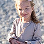 child, girl, smile, flower_headband, dress, long_sleeves, outdoor, sunlight, portrait, happy, hands, blurry_background, pebbles, young, cute, fashion, casual, person, daylight, skin