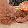 Lénaëlle a rejoint le concours — aidez-le/la à gagner de superbes lots ! baby, infant, tutu, headband, flower, peach, soft_towel, lying_down, cute, adorable, skin, hand, arm, face, indoors, table, fabric, decor, newborn, resting