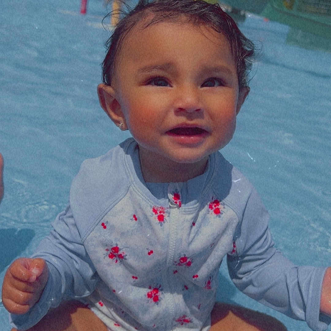 Sol is registered to the contest to win money with this photo: child, face, floral_pattern, fun, happy, legs, outdoor, play, pool, sitting, skin, slides, smiling, summer, sunny, swimsuit, toddler, trees, water, water_park