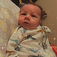 Sawyer is registered to the contest to win money with this photo: baby, infant, pajamas, dinosaur_pattern, pillow, geometric_pattern, face, cute, indoors, child, sparkle_filter, sleepwear, resting, newborn, soft_lighting, portrait, person, cozy, young_child, home