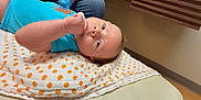 Sawyer is registered to the contest to win money with this photo: baby, infant, child, blanket, polka_dot, blue_clothing, hand, glove, indoor, floor, curious, lying_down, portrait, person, skin, head, face, young, support, casual