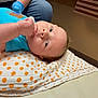 baby, infant, child, blanket, polka_dot, blue_clothing, hand, glove, indoor, floor, curious, lying_down, portrait, person, skin, head, face, young, support, casual
