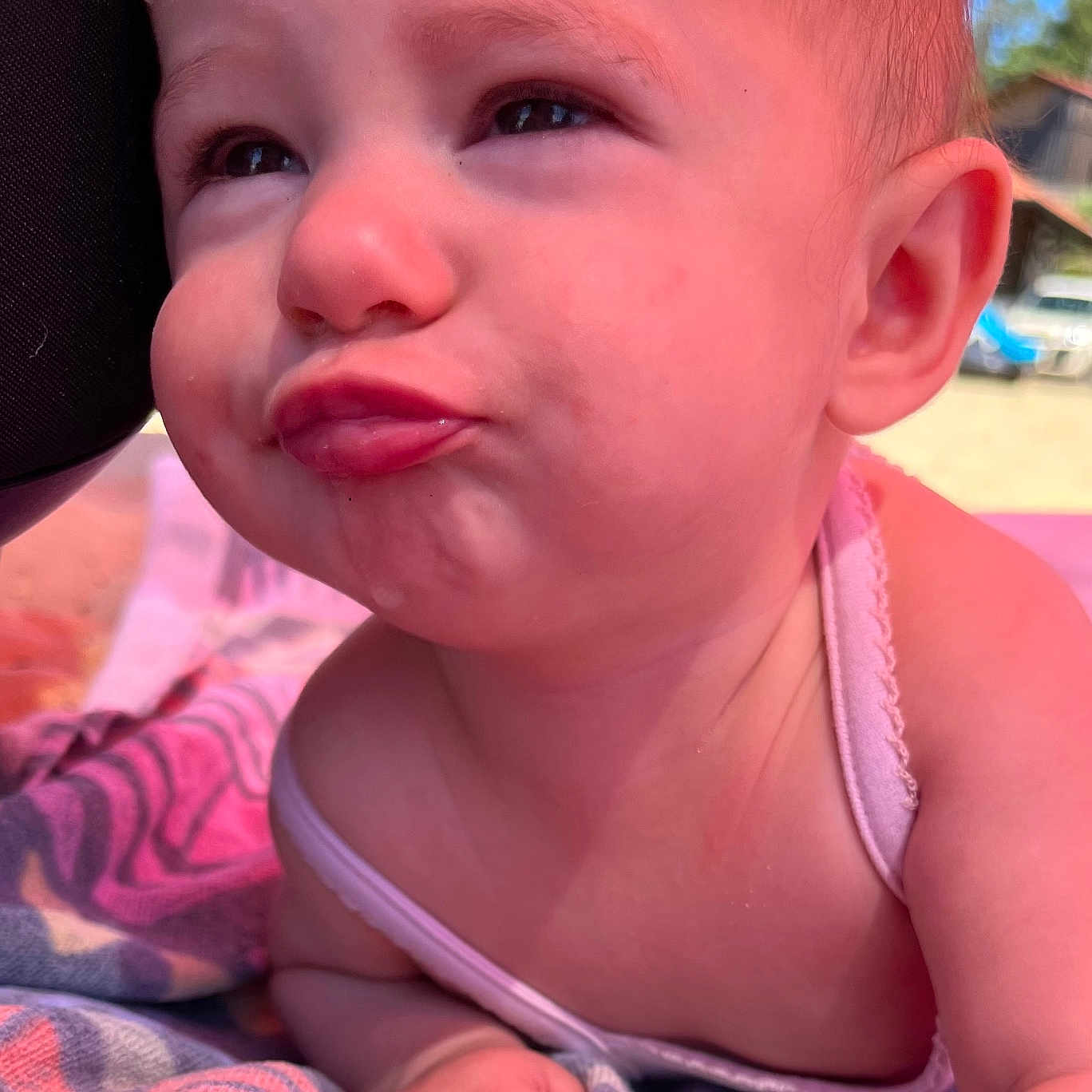 Alma participe au concours pour gagner de l'argent avec cette photo : arm, baby, building, child, closeup, expression, face, funny_face, head, infant, nature, outdoor, pink_clothing, playful, portrait, skin, summer, sunlight, towel, vehicle