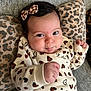 baby, bow, cheeks, child, couch, cozy, cute, face, fist, hair_accessory, heart_pattern, indoor, infant, leopard_print, pillow, portrait, resting, smiling, sweater, young