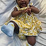 baby, child, smiling, yellow_dress, headband, white_blanket, sock, happy, infant, cute, lying_down, playful, floral_pattern, toddler, one_person, indoors, skin, face, hands, feet