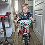 Jules a rejoint le concours — aidez-le/la à gagner de superbes lots ! child, bicycle, indoor, boy, red_bicycle, wooden_floor, curtains, window, door, adult, people, furniture, stool, casual_clothing, shorts, sneakers, living_room, conversation, handlebars, toy