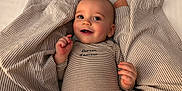 Jules participe au concours pour gagner de l'argent avec cette photo : baby, bed, child, cozy, cute, expression, face, hand, happy, infant, lying_down, newborn, onesie, person, portrait, skin, smiling, soft, striped_blanket, striped_clothing