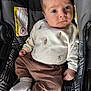 baby, car_seat, child, closeup, clothing, cozy, cute, expression, footwear, indoor, infant, looking, pants, patterned_fabric, portrait, seat, small_hands, socks, sweater, young_child