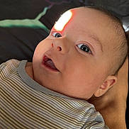 Thomas is registered to the contest to win money with this photo: arm, baby, blue_eyes, close_up, cute, expression, face, head, human, indoor, infant, laying_down, light, newborn, person, portrait, shadow, skin, striped_clothing, young_child