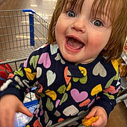 Emberleigh joined the competition — help win amazing prizes! toddler, child, shopping_cart, grocery_store, snack, happy, smiling, colorful_clothing, hearts_pattern, indoor, person, cute, young_child, holding_food, retail, aisle, casual, playful, fun, bright