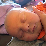 Richard is registered to the contest to win money with this photo: baby, sleeping, face, hand, closeup, infant, blanket, orange_clothing, peaceful, skin, portrait, newborn, child, soft, resting, indoors, cute, person, head, relaxing