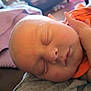 baby, sleeping, face, hand, closeup, infant, blanket, orange_clothing, peaceful, skin, portrait, newborn, child, soft, resting, indoors, cute, person, head, relaxing