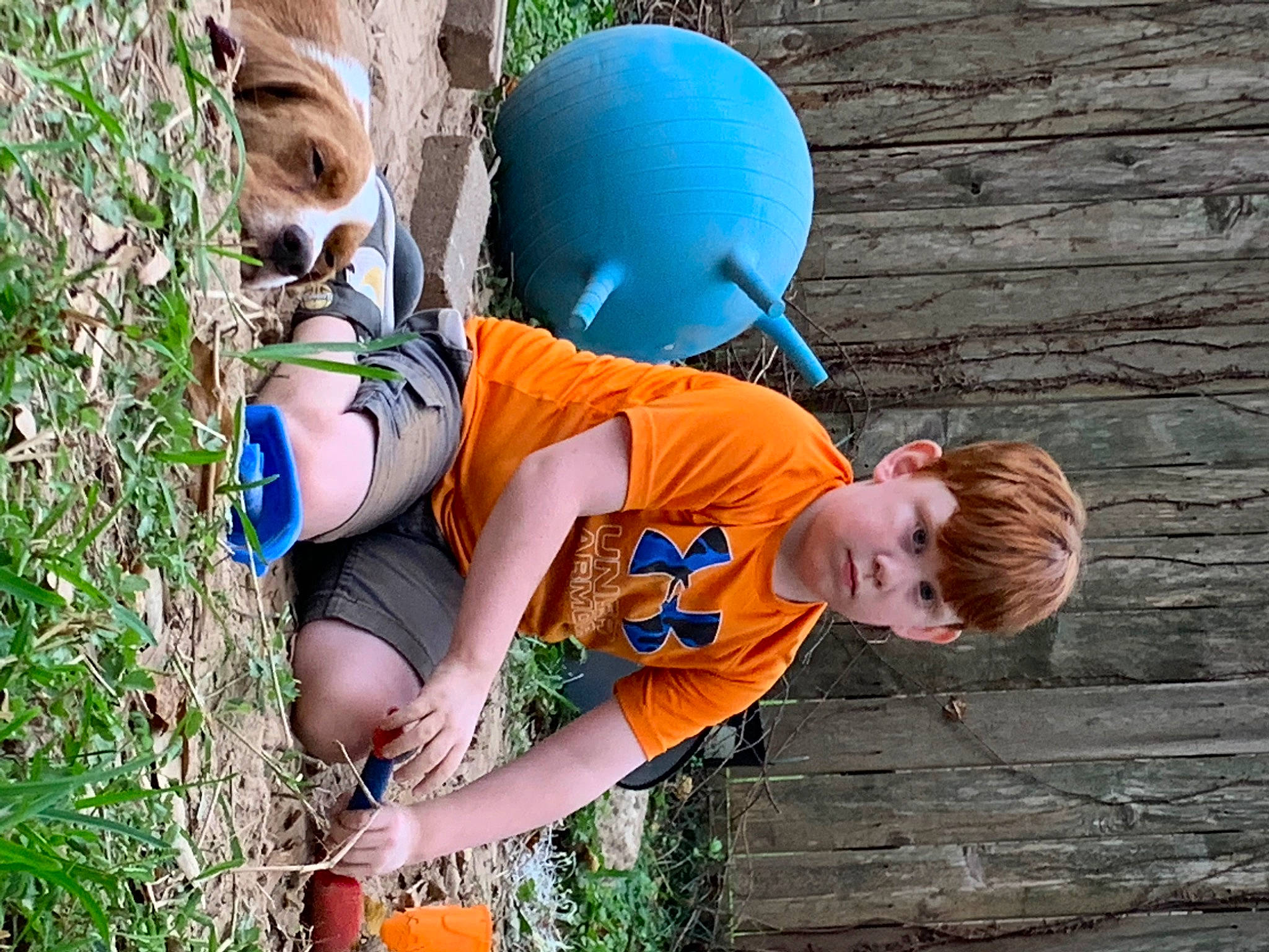 Michael is registered to the contest to win money with this photo: child, electric_blue, fun, grass, happy, leg, leisure, orange, people_in_nature, person, plant, recreation, sandal, shorts, sitting, sneakers, t_shirt, thigh, toddler, tree