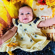 Aniyah is registered to the contest to win money with this photo: baby, smile, dress, bee_pattern, polka_dot, yellow, black, sunflower, flower, blanket, happy, infant, cute, lying_down, child, nature_theme, floral, bright_colors, cheerful, portrait
