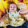 baby, smile, dress, bee_pattern, polka_dot, yellow, black, sunflower, flower, blanket, happy, infant, cute, lying_down, child, nature_theme, floral, bright_colors, cheerful, portrait