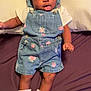 Ahzani is registered to the contest to win money with this photo: baby, infant, child, denim_overalls, floral_pattern, white_tshirt, socks, bed, pillow, purple_sheet, cute, lying_down, indoors, person, skin, face, hair, expression, small_baby, clothing