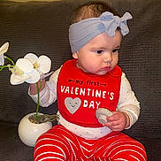 Avia joined the competition — help win amazing prizes! baby, child, headband, bib, valentines_day, flower, orchid, plant, pot, couch, striped_pants, red, white, sitting, indoors, clothing, person, cute, holding, portrait