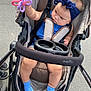 Avia is registered to the contest to win money with this photo: baby, stroller, toy, headband, blue_socks, child, infant, outdoor, pavement, curious, evenflo, seatbelt, footwear, clothing, person, baby_toy, cute, baby_girl, child_in_stroller, playing
