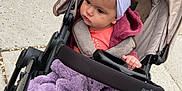 Avia is registered to the contest to win money with this photo: baby, baby_carriage, blanket, bundle, casual, child, clothing, curious, evenflo, headband, outdoor, person, portrait, purple, sidewalk, stroller, toddler, urban, warm, wheelchair_accessory