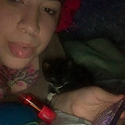 Toast joined the competition — help win amazing prizes! person, cat, selfie, bed, blanket, phone, piercing, bonnet, dark, indoor, animal, pet, hand, face, portrait, cozy, night, lying_down, black_cat, casual