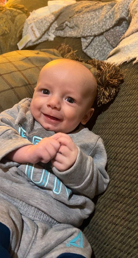 Ezekiel is registered to the contest to win money with this photo: baby, baby_toddler_clothing, cheek, child, chin, fun, gesture, grass, happy, head, joy, nose, people_in_nature, person, plant, sitting, skin, smile, thumb, toddler