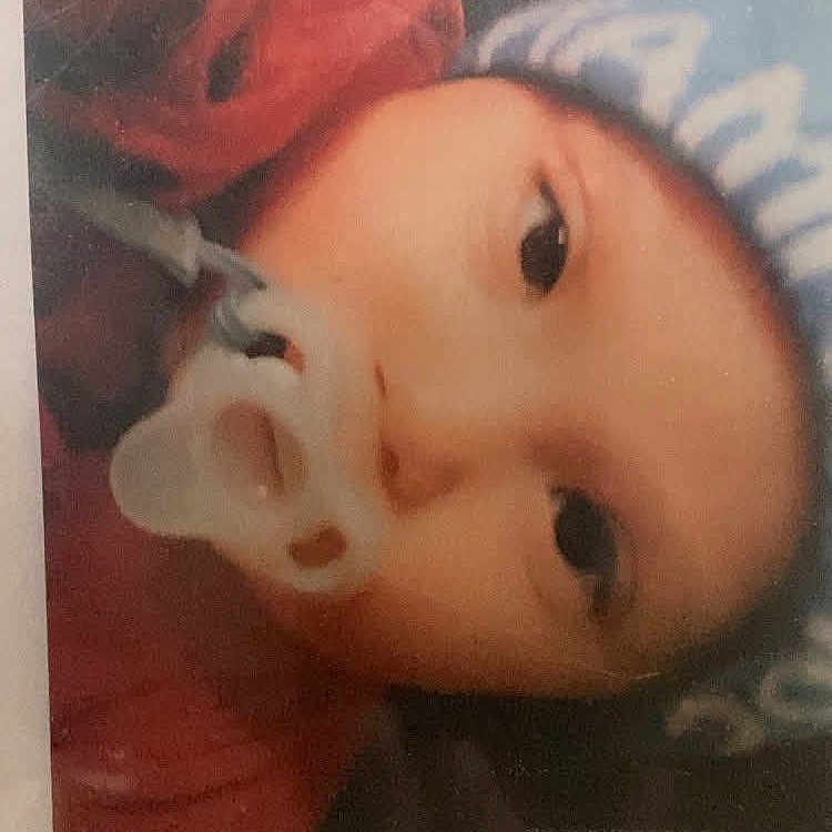Elijah is registered to the contest to win money with this photo: baby, infant, child, portrait, face, eyes, pacifier, red_clothing, lying_down, close_up, indoors, bed, blanket, blue_blanket, photograph, glare, reflection, rotated_image, soft_focus, candid