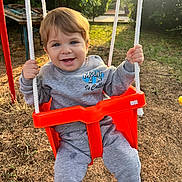 Mehmetcan participe au concours pour gagner de l'argent avec cette photo : toddler, child, swing, playground, orange_swing, smiling, happy, outdoor, sunlight, clothing, grey_sweatshirt, grey_pants, grass, trees, rope, play, young_child, person, daylight, nature