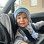 baby, blue_eyes, car_interior, car_seat, child, closeup, cozy, cute, gray_sweater, happy, indoor, knitted_hat, person, portrait, safety, seatbelt, smiling, toddler, winter_clothing, young_child