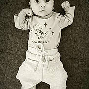Raphaël a rejoint le concours — aidez-le/la à gagner de superbes lots ! baby, infant, child, dinosaur_graphic, clothing, pants, socks, lying_down, monochrome, black_and_white, cute, portrait, serious_face, raised_fists, text_on_clothing, soft_fabric, indoor, comfort, small_person, casual_wear