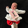 baby, infant, one_month, clothing, white_top, red_pants, frilly_skirt, card, floral_design, lying_down, black_background, cute, celebration, milestone, newborn, soft_booties, baby_face, happy, small_hands, portrait