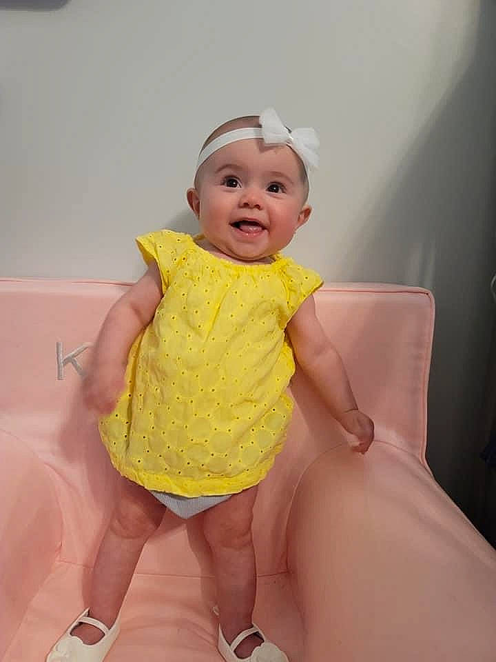 Kendra is registered to the contest to win money with this photo: baby, baby_toddler_clothing, cheek, dress, eye, flash_photography, fun, gesture, happy, headwear, human_body, iris, lip, one_piece_garment, person, pink, skin, sleeve, smile, thigh