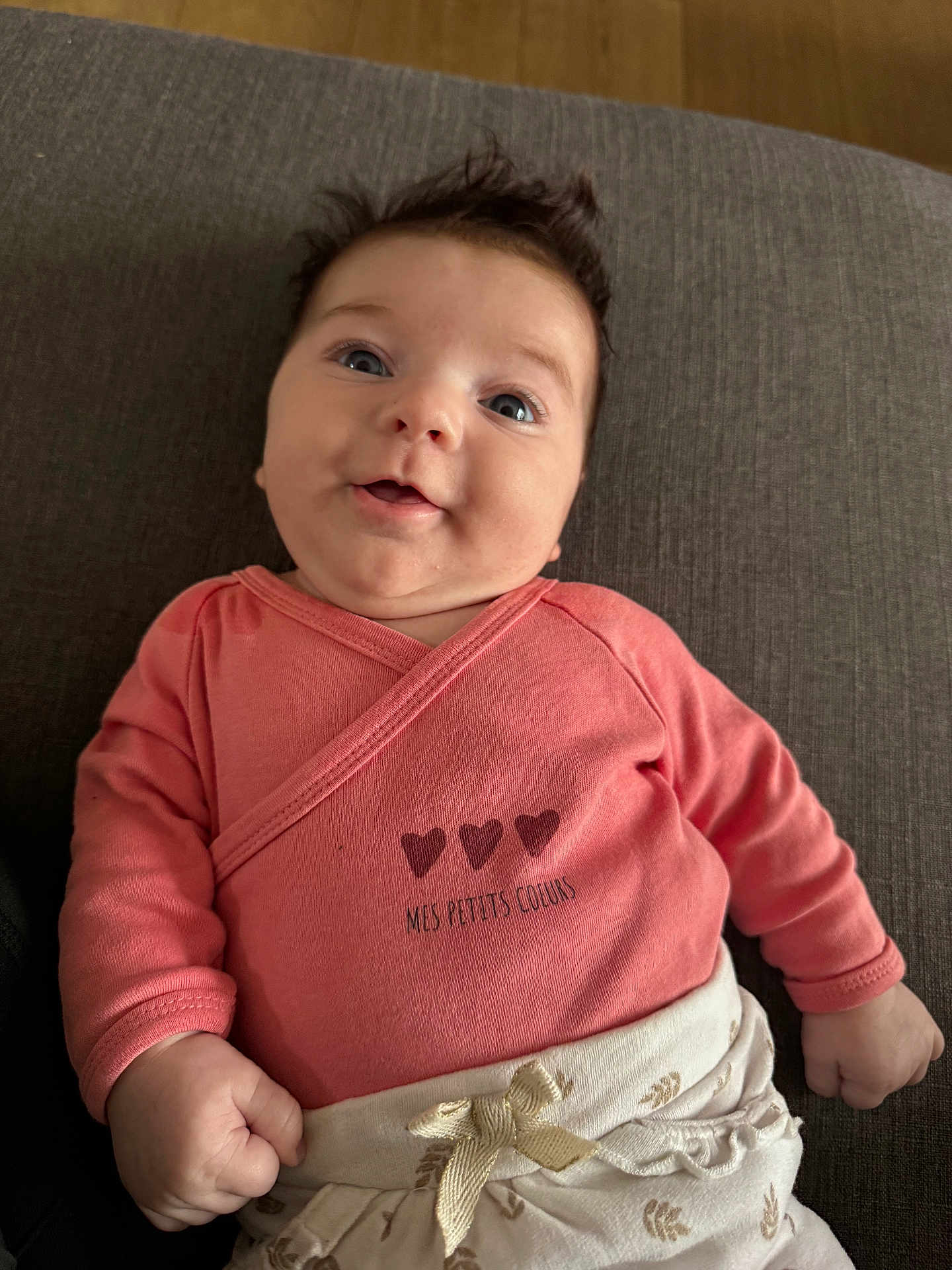 Roxane participe au concours pour gagner de l'argent avec cette photo : baby, infant, child, pink_clothing, smiling, happy, portrait, couch, furniture, indoor, face, hand, eyes, hair, clothing, bow, fabric, cute, person, lying