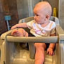 Annabeth joined the competition — help win amazing prizes! baby, child, high_chair, indoor, cute, infant, unicorn_shirt, curious, looking_away, legs, feet, hand, plastic_chair, casual_clothing, seated, portrait, soft_background, chubby, toddler, young_child