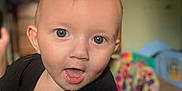 Annabeth joined the competition — help win amazing prizes! baby, child, face, blue_eyes, curious, indoor, blurred_background, high_chair, black_shirt, infant, tongue_out, closeup, person, home, colorful, toy, seat, expression, young_child, portrait