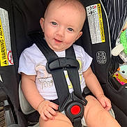 Annabeth joined the competition — help win amazing prizes! baby, car_seat, child, smile, safety_harness, warning_label, toy, cute, infant, seat_belt, clothing, person, sitting, indoor, face, hand, legs, comfort, protection, bright