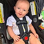 baby, car_seat, child, smile, safety_harness, warning_label, toy, cute, infant, seat_belt, clothing, person, sitting, indoor, face, hand, legs, comfort, protection, bright