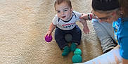 Waylon is registered to the contest to win money with this photo: baby, child, toddler, woman, carpet, floor, ball, toy, sitting, playing, indoor, person, clothing, sock, trash_bin, hairband, jeans, barefoot, home, interaction