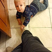 Nolann participe au concours pour gagner de l'argent avec cette photo : baby, blond_hair, cabinet, child, crawling, curious, floor, gaze, hand, indoor, jeans, kitchen, looking_up, person, playful, portrait, sock, sweater, tile_floor, toddler
