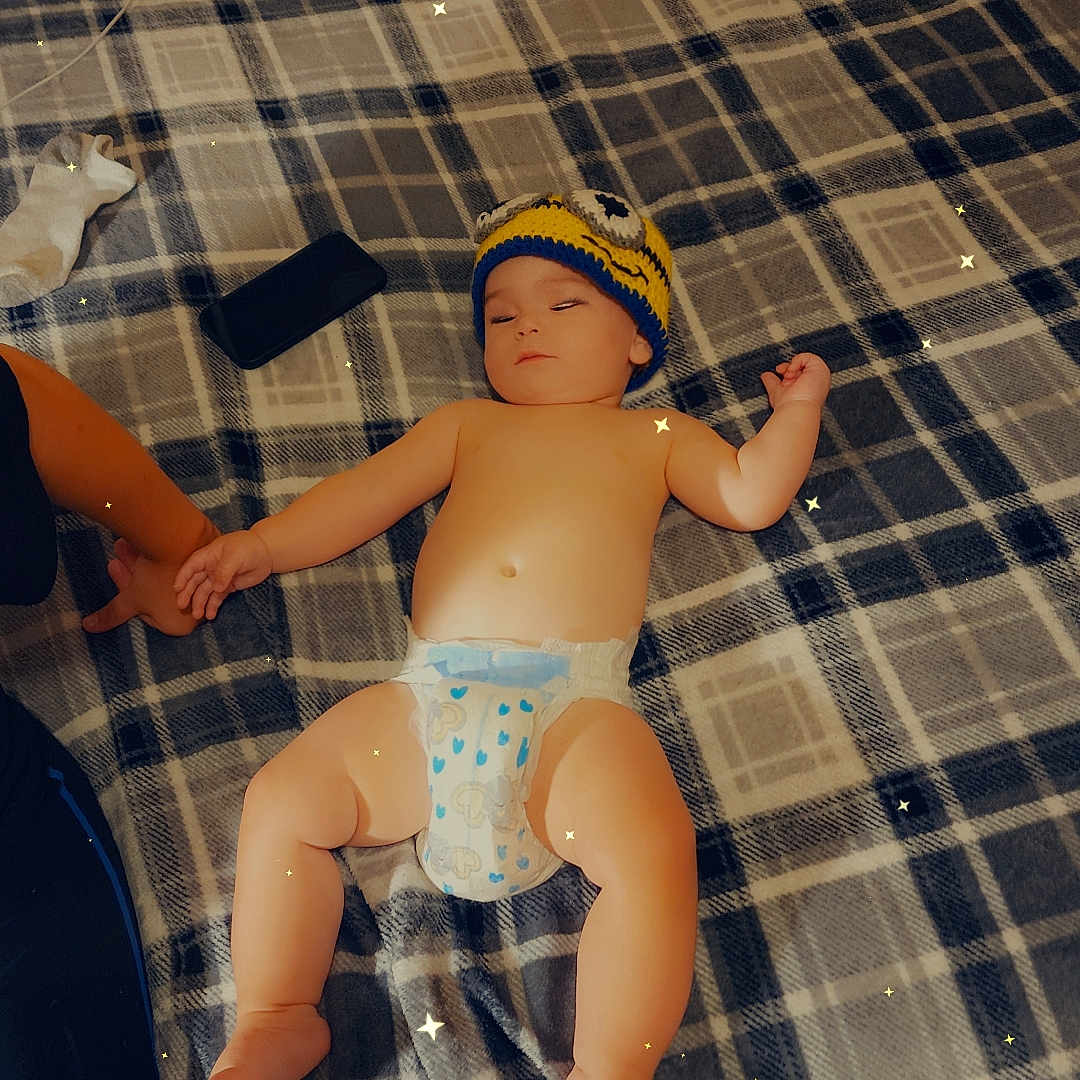Garrett is registered to the contest to win money with this photo: baby, back, bed, bedroom, bodypart, cap, clothing, couch, diaper, electronics, face, finger, furniture, hand, hat, head, person, photography, portrait, remotecontrol
