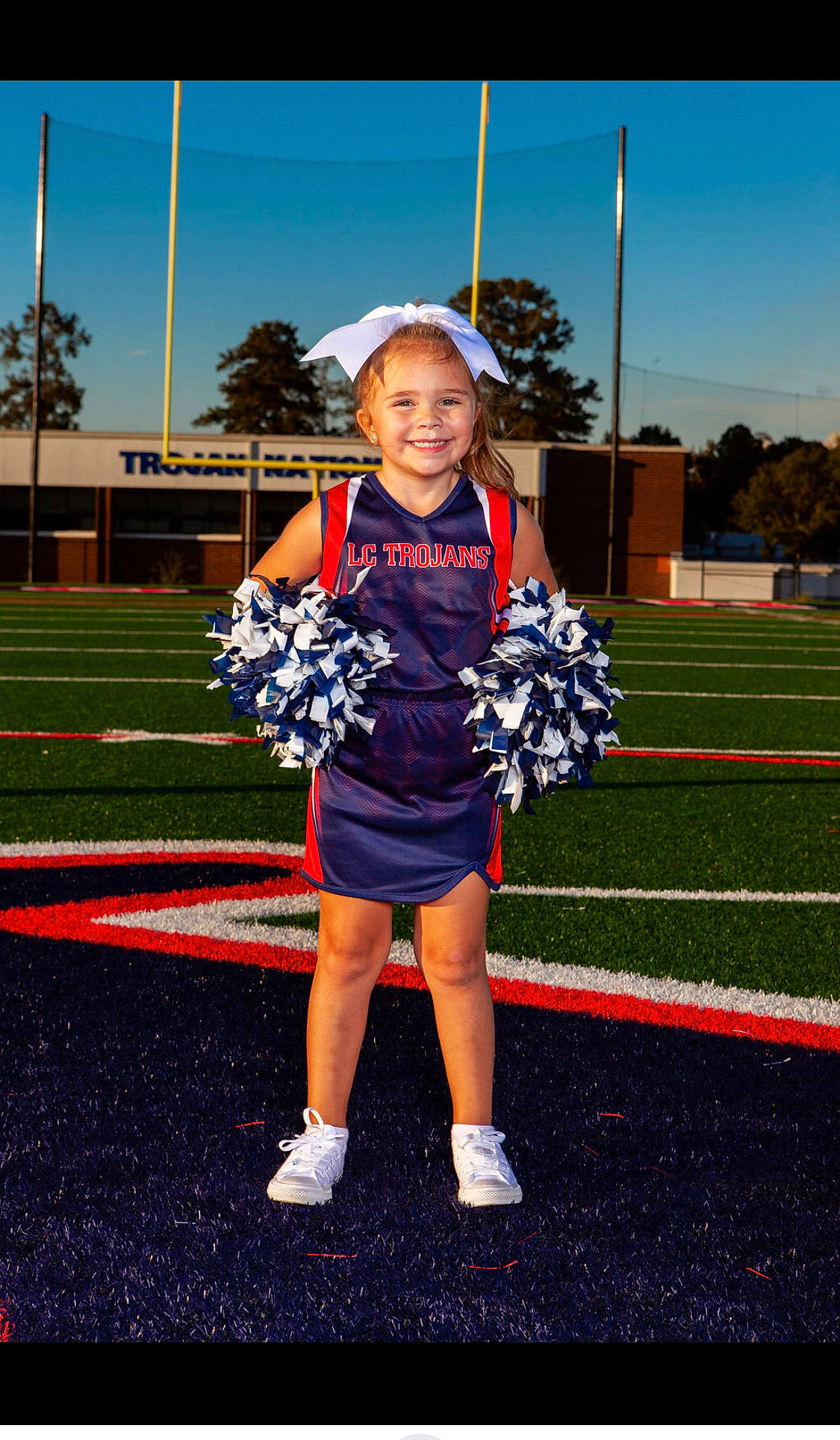 Khloé is registered to the contest to win money with this photo: ball_game, cheerleading, cheerleading_uniform, competition_event, electric_blue, event, face, grass, joy, person, player, sky, smile, sports, sports_uniform, sportswear, t_shirt, team, team_sport, toddler