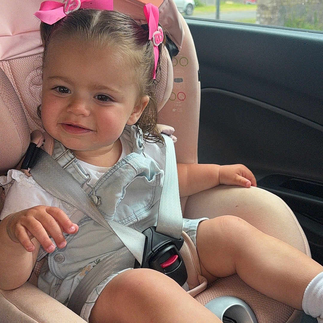 Aiyla Marie is registered to the contest to win money with this photo: car_interior, car_seat, child, clothing, daylight, face, hair_bows, person, pink, rain_drops, seatbelt, shoes, shorts, sitting, smiling, socks, suburban, toddler, white_shirt, window