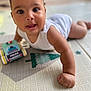 baby, child, infant, play_mat, toy_car, police_toy, white_clothing, crawling, hand, face, eyes, smile, indoor, floor, cute, curious, skin, person, young_child, early_learning