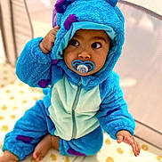 Manoé participe au concours pour gagner de l'argent avec cette photo : baby, blue, child, costume, curious, cute, expression, face, floor_mat, hand, hood, indoor, infant, onesie, pacifier, plush, purple, sitting, soft, warm_clothing