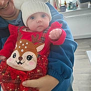 Julia a rejoint le concours — aidez-le/la à gagner de superbes lots ! baby, child, adult, person, hat, pom_poms, red_clothing, plaid, deer_design, smile, hand, indoor, kitchen, window, radiator, floor, blue_jacket, holding, cute, festive