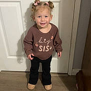 Dahlia is registered to the contest to win money with this photo: child, toddler, girl, portrait, smiling, standing, indoors, door, doorknob, sweater, big_sis, pink_bows, pigtails, black_pants, boots, wood_floor, home, full_body, happy, photograph