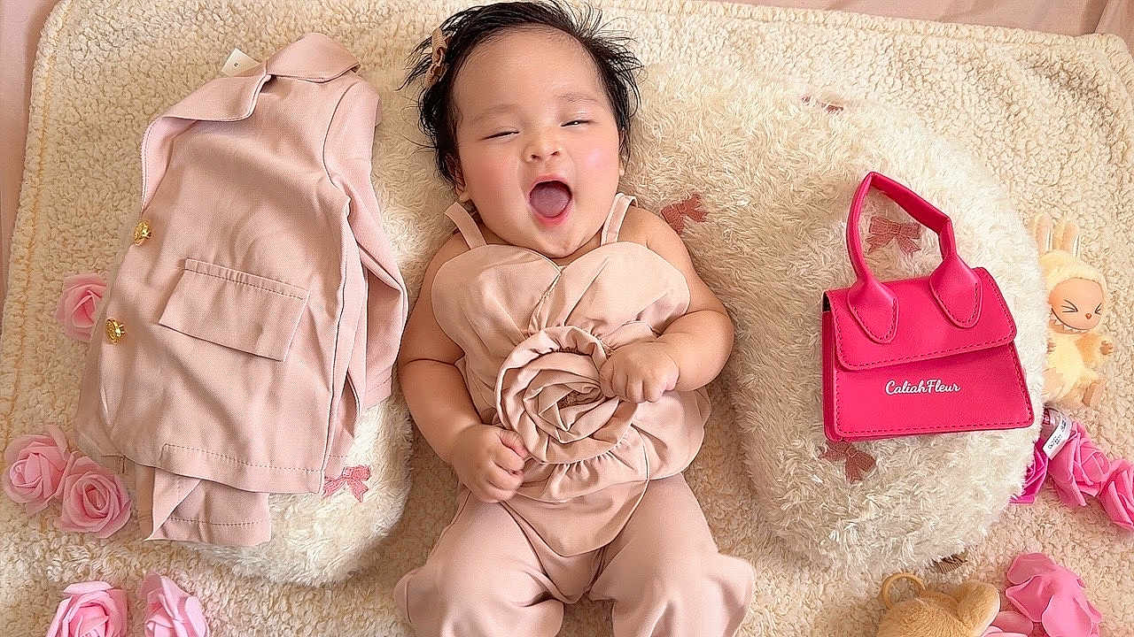 Caliah Fleur joined the competition — help win amazing prizes! baby, infant, pink_outfit, rose, cushion, plush_toy, handbag, flowers, smiling, happy, lying_down, indoors, cute, child, soft_texture, decor, small_bag, toy, person, portrait