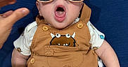 Asher joined the competition — help win amazing prizes! baby, blue_background, button, child, clothing, cute, expression, face, hair, hand, indoor, infant, monster_prints, mouth_open, orange_surface, person, romper, short_sleeves, sitting, sunglasses