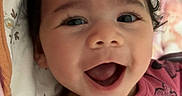Melody is registered to the contest to win money with this photo: adorable, baby, cheerful, child, closeup, clothing, cozy, curly_hair, cute, cute_outfit, expression, face, happy, indoors, infant, lying_down, person, pink_blanket, portrait, smiling