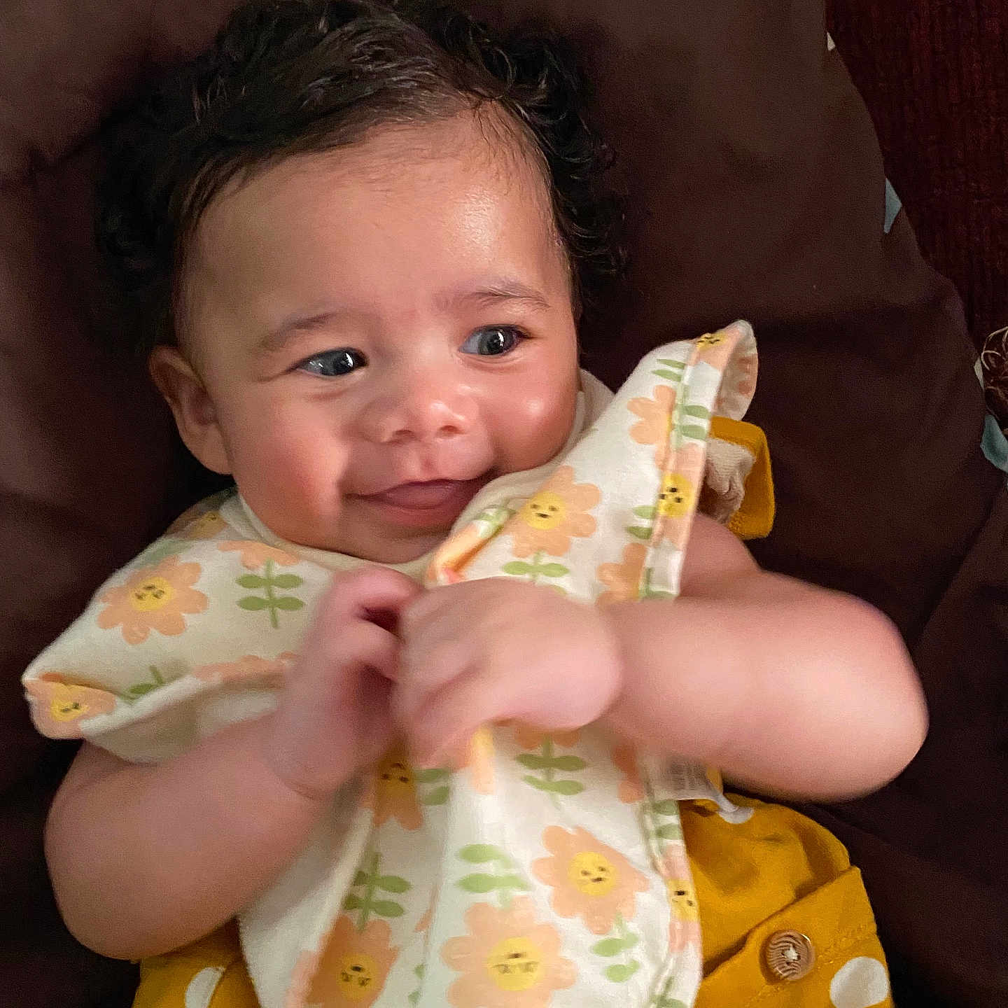 Melody joined the competition — help win amazing prizes! baby, child, smiling, curly_hair, bib, yellow_clothing, polka_dots, face, hand, portrait, infant, happy, cute, skin, closeup, resting, indoors, person, fabric, clothing